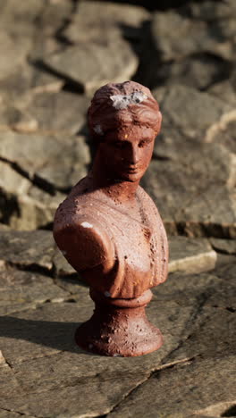 ancient terracotta bust on rocks