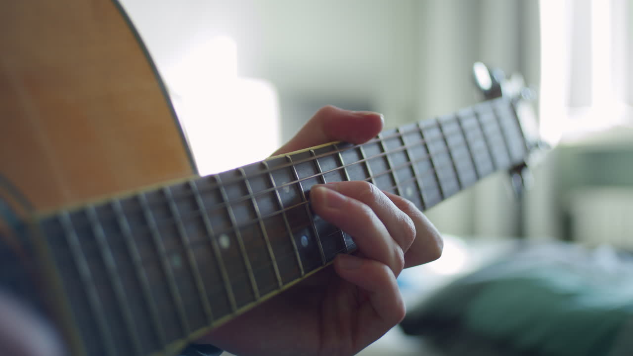 A guitar being played on. Nice lighting and shallow depth of field. Only one hand is in focus. Nice slide in and out of focus with the hand.