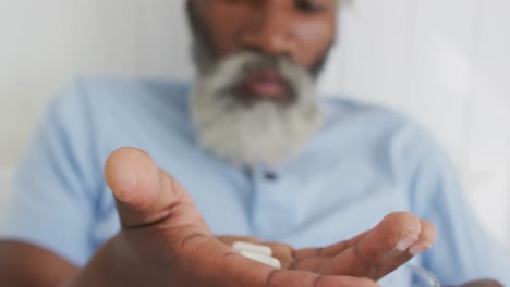 senior man taking pills in bed at home