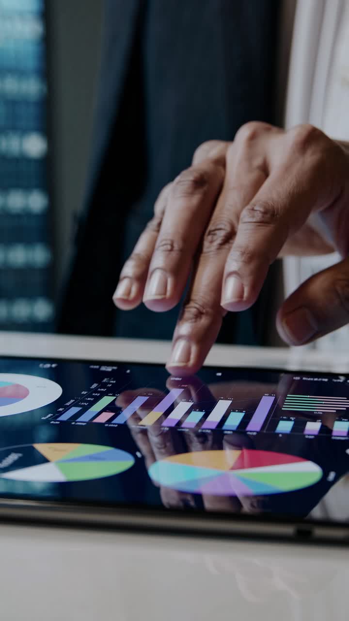 Hand Tapping on Tablet Displaying Business Charts