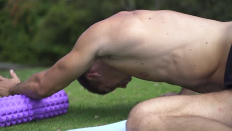 Joven-Caucásico-En-Forma-Atractiva-Masculina-Haciendo-Ejercicio-Al-Aire-Libre-Con-Rodillo-De-Espuma-Ejercicio-Dorsal-Con-Fondo-De-Vegetación-Verde-A-Cámara-Lenta-60-Fps