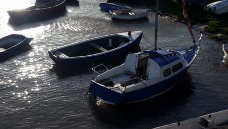 looking down on sunny boats docked on shimmering harbour water reflections