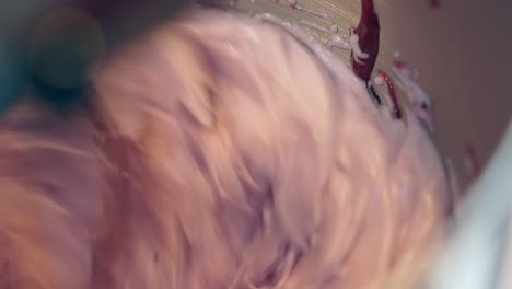 el mezclador agita en círculos crema de pastel rosa con un batidor grande