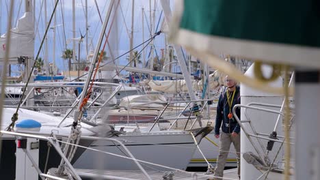 Slow-motion-shot-of-a-young-man-walking-along-the-dock-towards-his-yacht