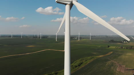 Flying-up-alongside-a-spinning-wind-generator-in-the-middle-of-a-field-on-a-sunny-summer-day