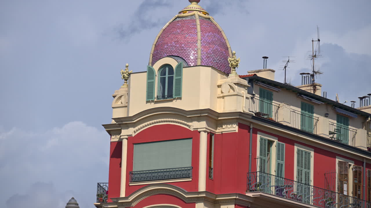 The facade of a Red building in Place Massena in daylight in Nice, France