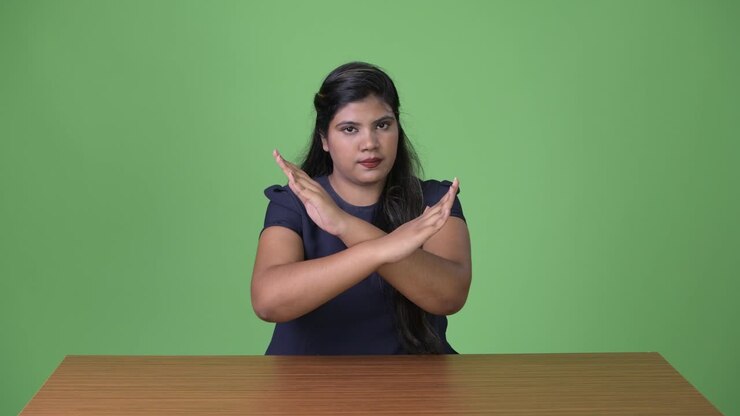 Young overweight beautiful Indian businesswoman against green background
