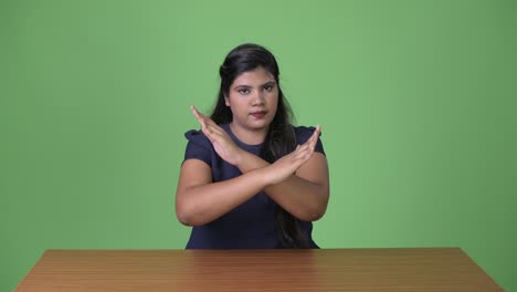 young overweight beautiful indian businesswoman against green background