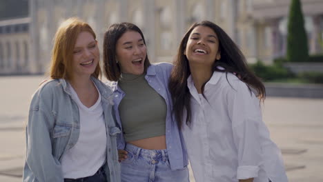 multi ethnic happy female friends hug and laugh together