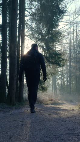 hombre caminando por un bosque de invierno al amanecer