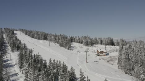 skiers going downhill on kope ski resort ribnica one track in slovenia, aerial dolly left shot