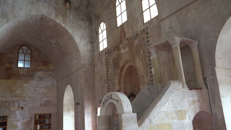 First-we-see-the-hewn-stone-pulpit-of-Zinciriye-Madrasa,-then-the-camera-shifts-upwards-towards-the-cut-stone-walls-and-the-dome