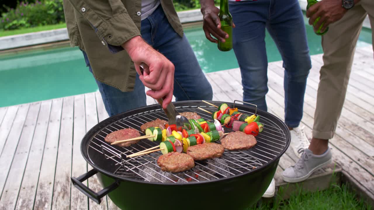 Diverse mandlige venner skåler med grønne flasker på terrassen, mens varme kul får grillmesteren til at vende burgere