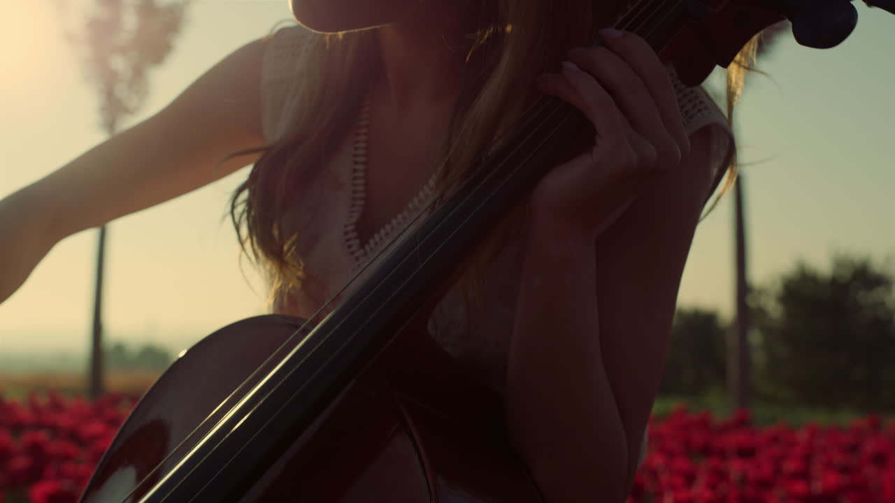 Closeup inspired young woman playing cello in blooming summer garden outdoors.