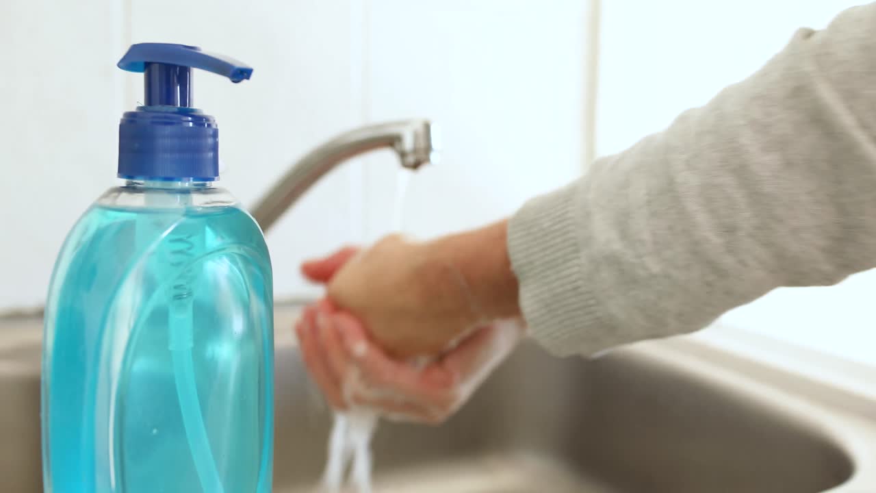 donna caucasica che si lava le mani con il sapone a casa