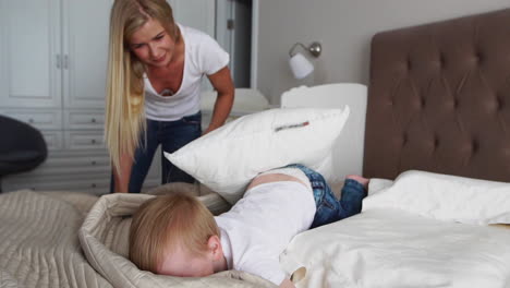 young mother and father with her 2 years old little son dressed in pajamas are relaxing and playing in the bed at the weekend together, lazy morning, warm and cozy scene. pastel colors, selective focus