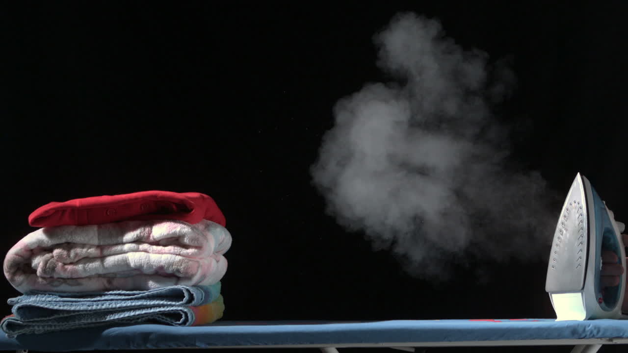 vapor saliendo de un hierro en una tabla de planchar con ropa
