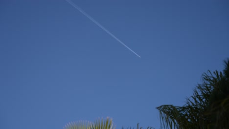 airplane leaves contrail wake in the blue sky above cannes france, looking up shot