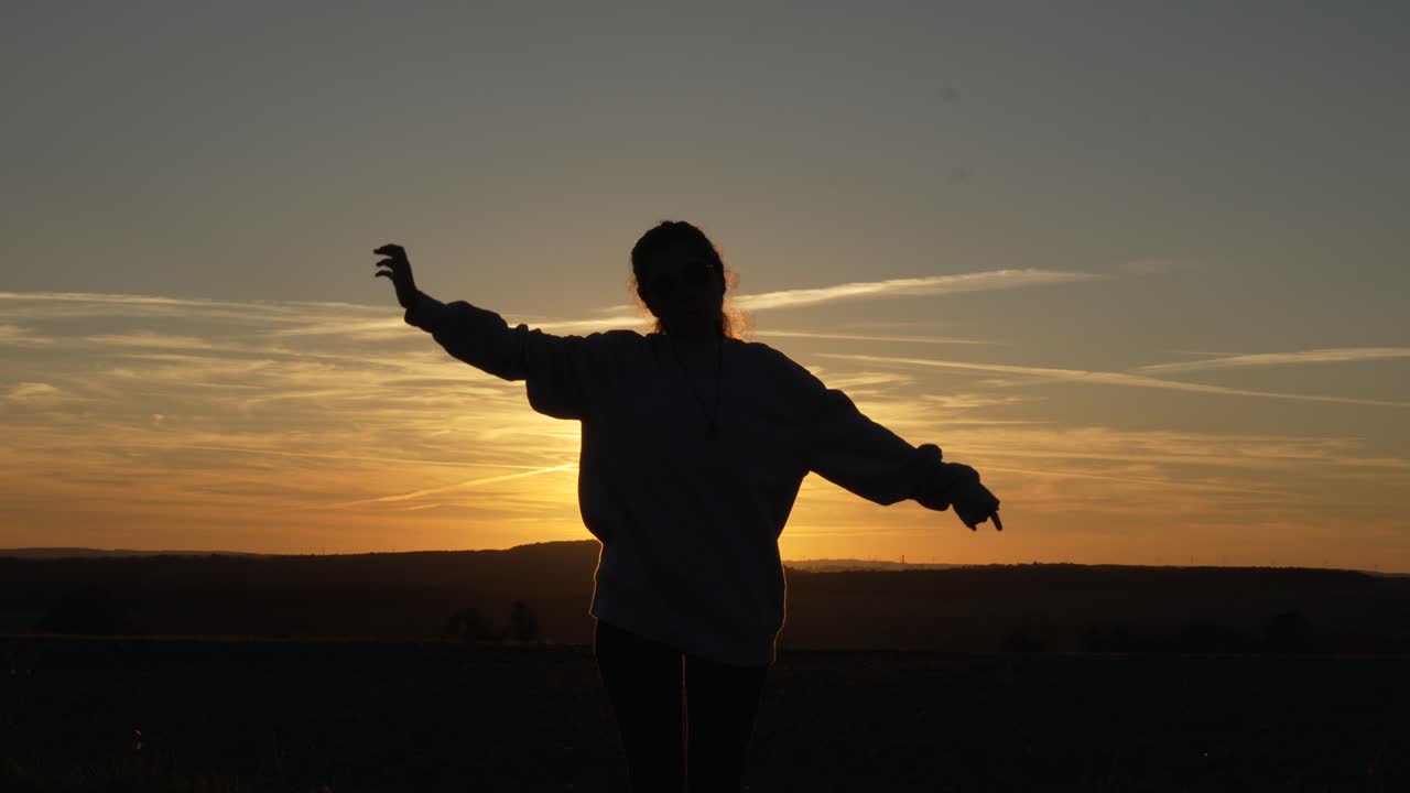 Silhouette femminile che fa stretching mattutino all'alba, ballando vibrazioni positive.