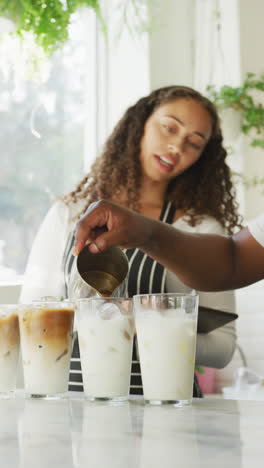 video vertical de un barista afroamericano y una barista preparando café en una cafetería