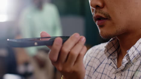 speaking into smartphone, man using voice command feature in office setting