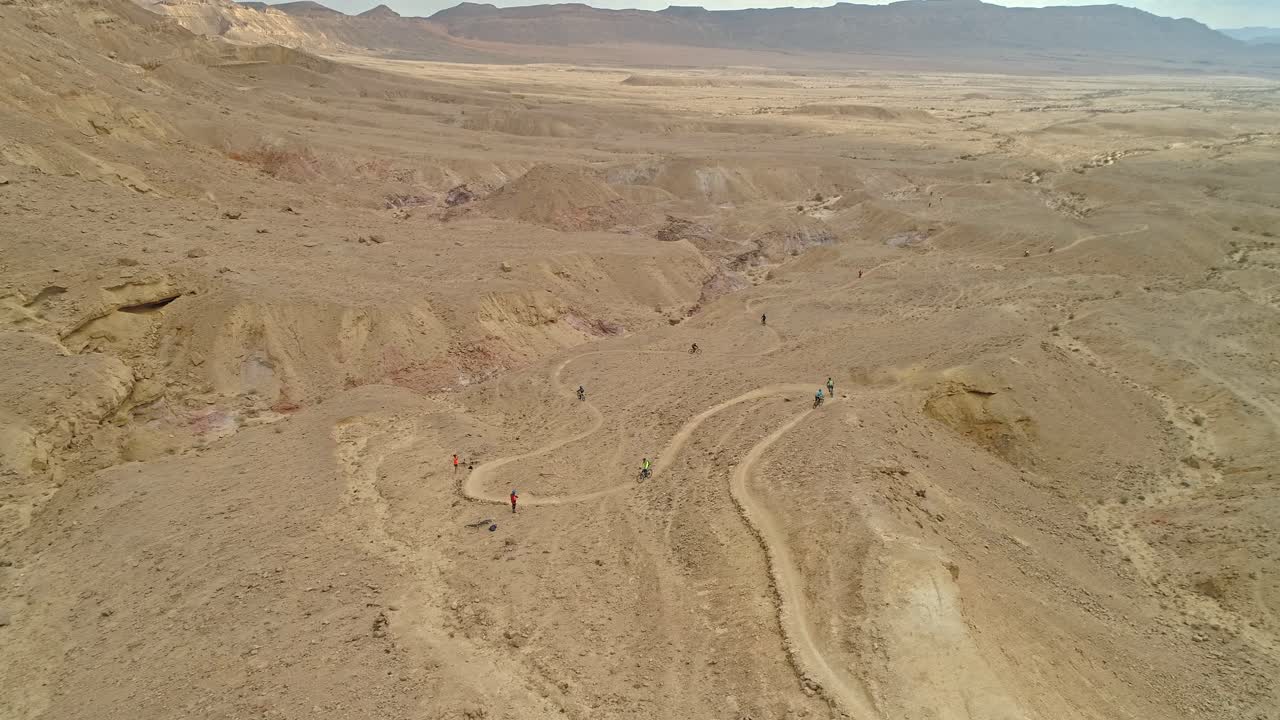 사막 절벽의 자전거 도로를 달리는 자전거 라이더 그룹의 공중 영상