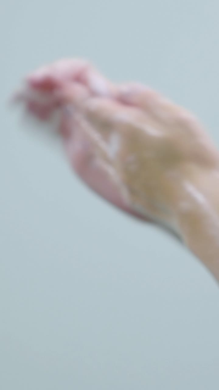Close-up of wet hands washing with soap, demonstrating hygiene and cleanliness in a minimalistic setting