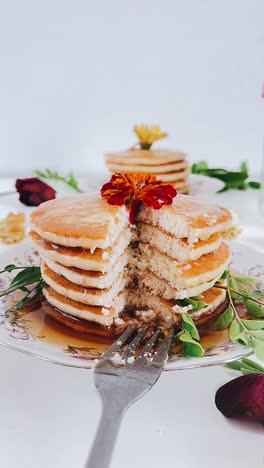 delicious stacked pancakes with syrup and flowers