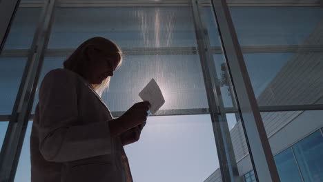 A-Passenger-With-A-Boarding-Pass-In-His-Hands-Is-Standing-At-A-Large-Window-Of-The-Airport-Terminal