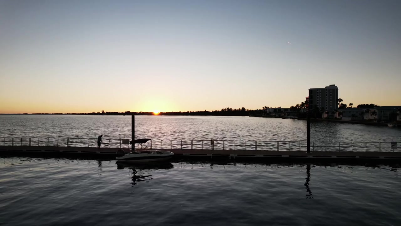 A picturesque landscape where one can enjoy a breathtaking view of the sunset over a tranquil body of water intersected by a pier.