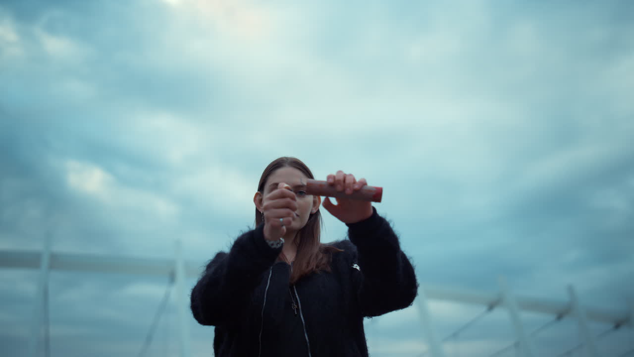 도시 거리에서 카메라를 보는 소녀. 라이터와 연기 폭탄을 들고 있는 여자