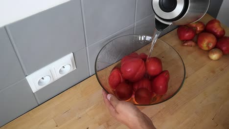 poner agua encima de los tomates rojos que están bien colocados en un recipiente de vidrio