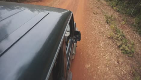 jeep driving down red dirt road in a jungle