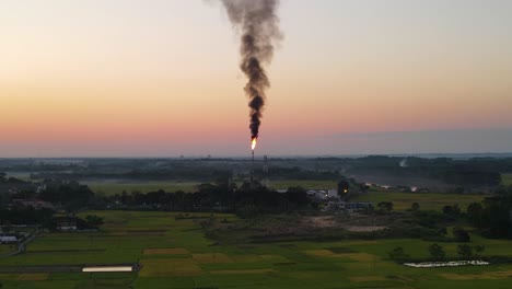 vista aérea de la quema de gas de la tubería en una planta de gas junto a las tierras de cultivo