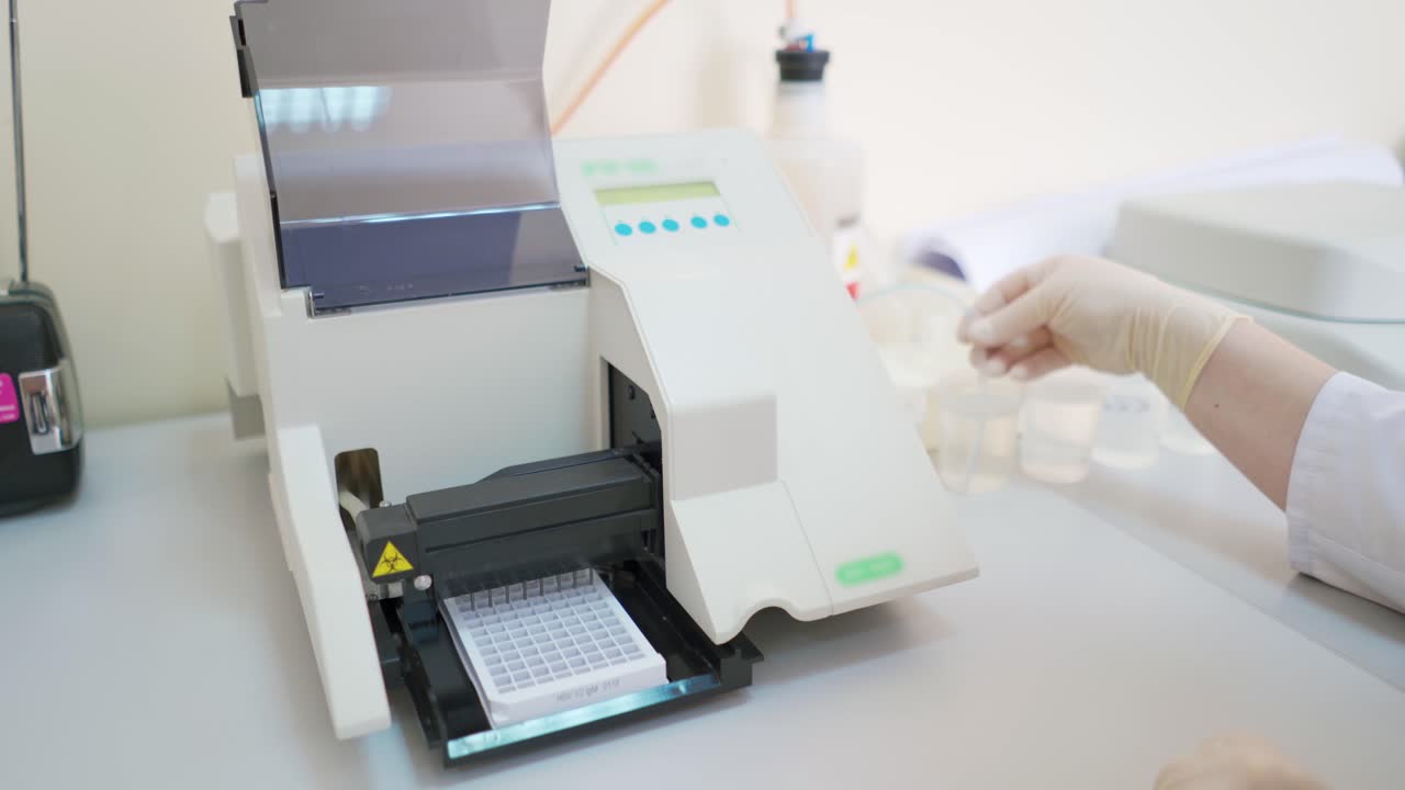 Automated equipment in the laboratory. Modern machine for making sample researches. Medical worker controls the work of robotic machine.