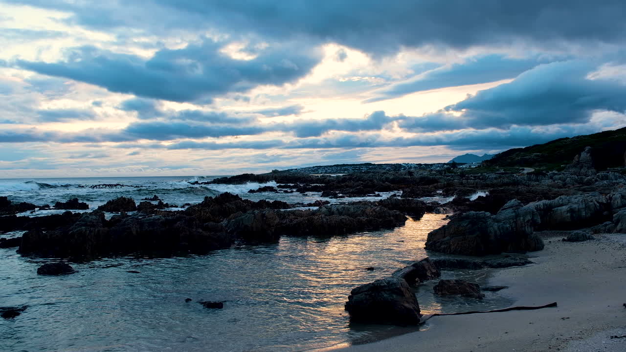 dolly sobre la playa rocosa al atardecer con nubes dramáticas rodando con la tormenta