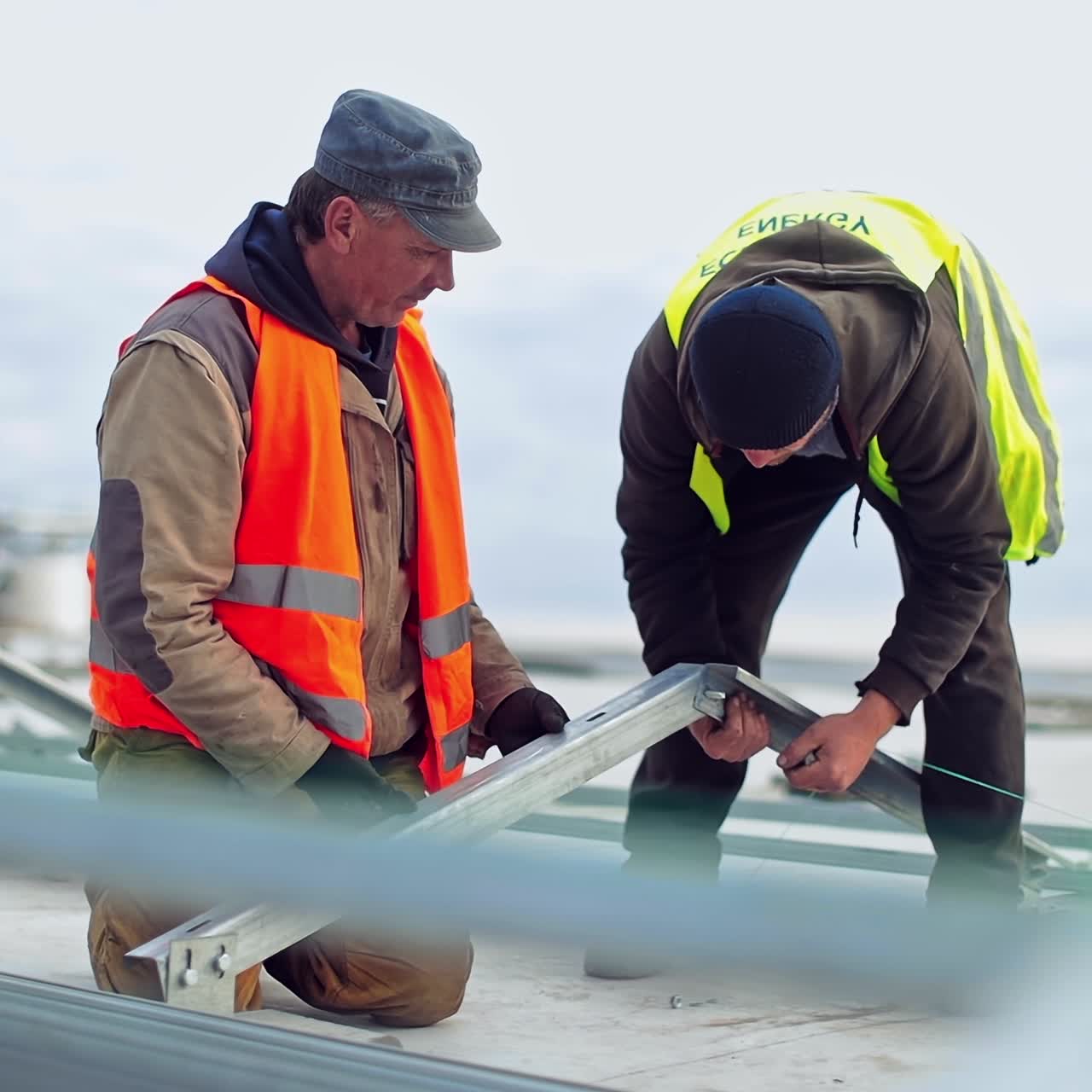 Construction of a new solar farm on a roof. Two engineers installing metal basis for future sunny batteries. Solar panels installation.