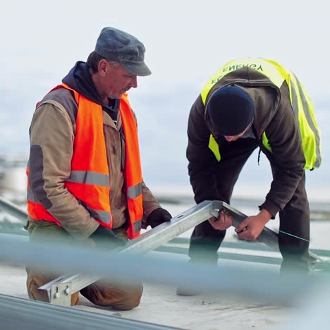 construction of a new solar farm on a roof. two engineers installing metal basis for future sunny batteries. solar panels installation.