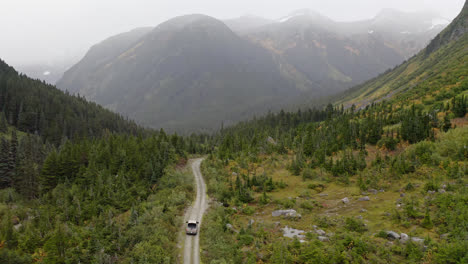 Aerial,-white-truck-drive-on-rural-road-between-mountain-valley,-British-Colombia