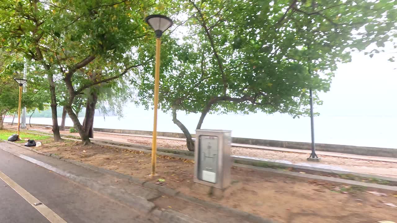 A serene drive along a tree-lined road by Nopparat Thara Beach, capturing the tranquil seaside atmosphere in Krabi, Thailand