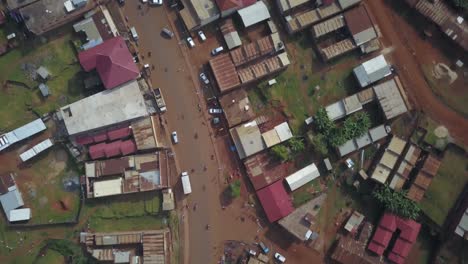 Overhead drone view of Kapchorwa Town showing scattered traffic along Kapchorwa–Suam Road, flanked by buildings and red earth terrain in Uganda's eastern highland region.