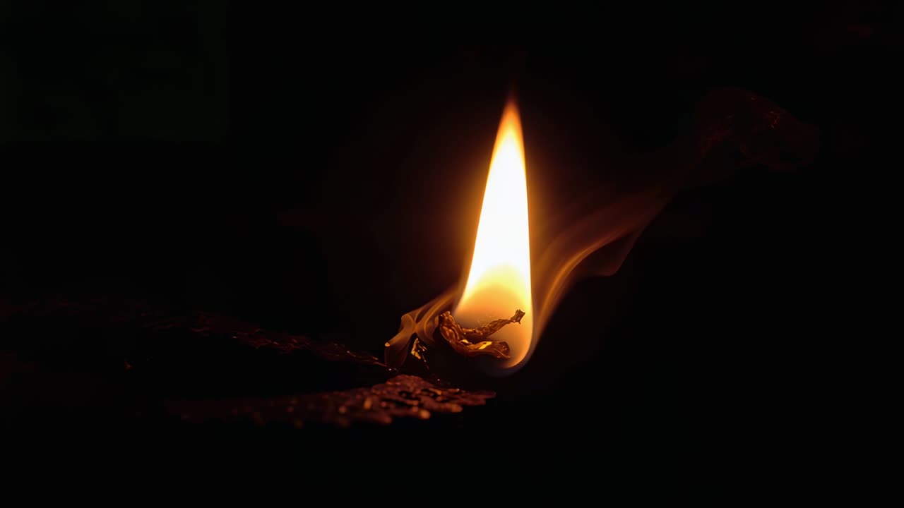 Igniting match head, flame flickering, smoke curling and match melting, against dark background