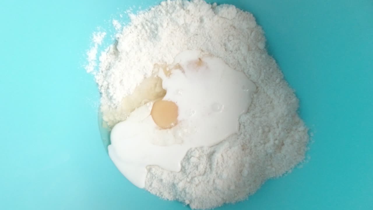 vista superior leche blanca vertida sobre la mezcla de bizcocho de harina y huevos en un tazón azul