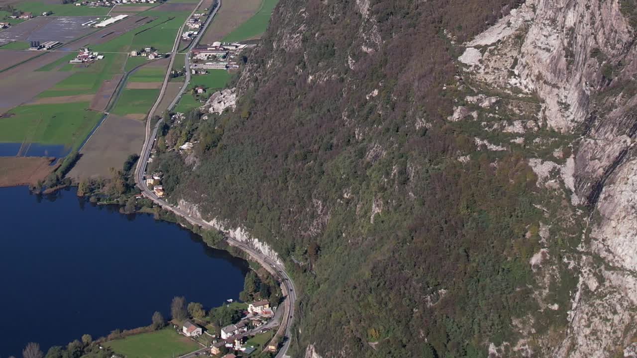 Drone view of lush green slopes and tranquil water in the Italian Alps