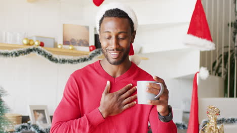 hombre afroamericano feliz con sombrero de papá noel y haciendo una llamada de video.