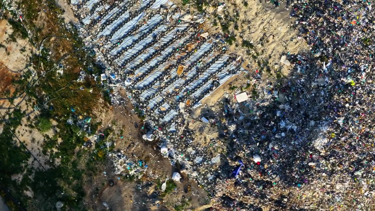 Landfill waste site shows large amounts of garbage and plastic debris. Contaminated area poses risks for diseases like hantavirus. Rodents are present in unsanitary conditions.