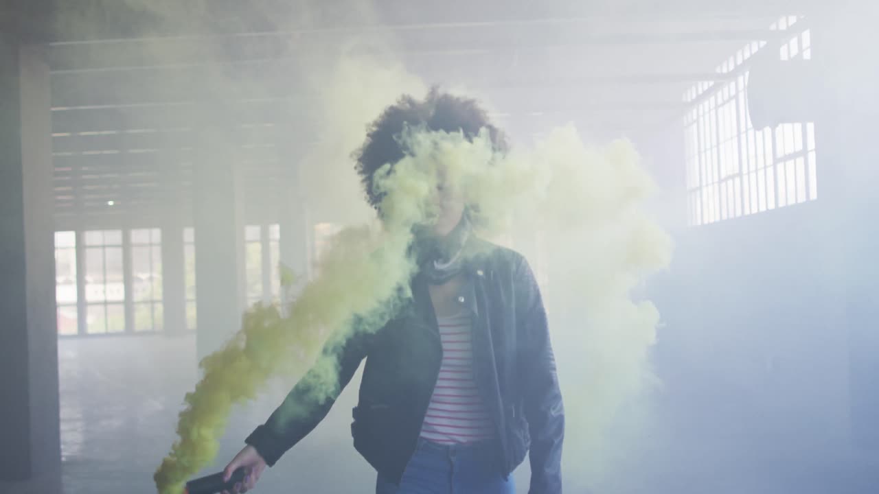 mujer de raza mixta sosteniendo bengala verde caminando a través de un edificio vacío