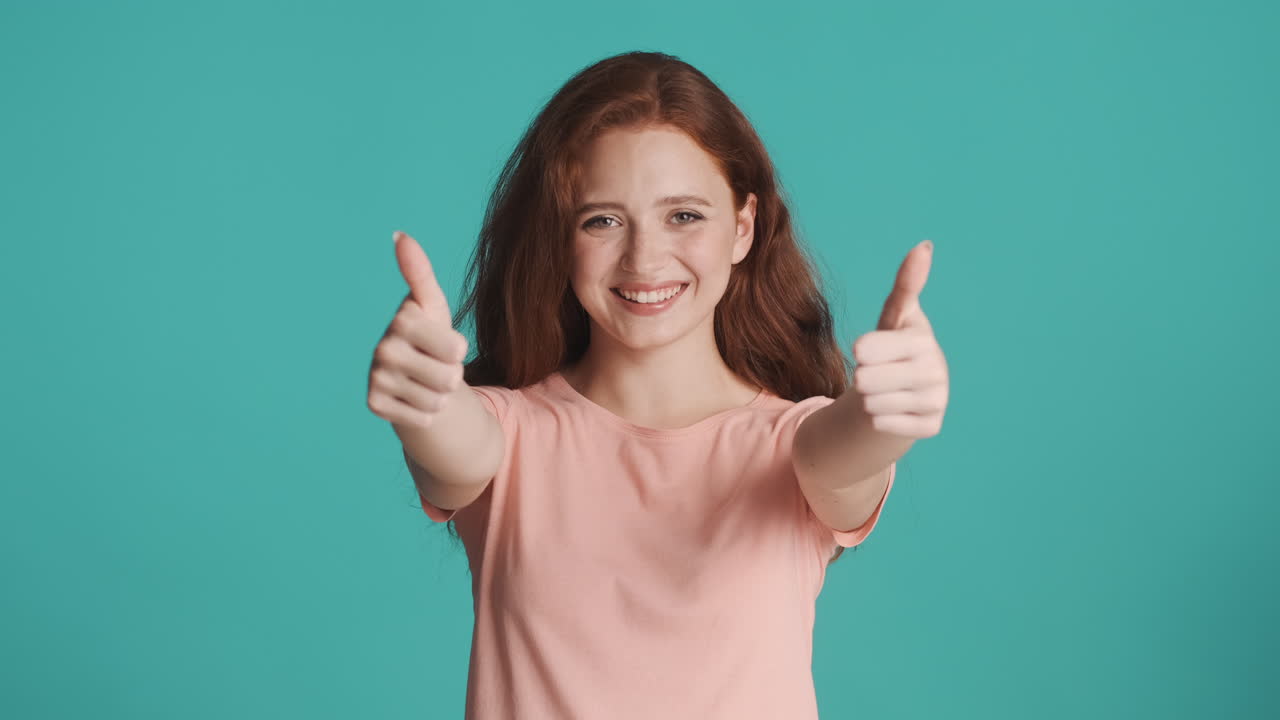 은 머리의 소녀가 르키즈색 배경에서 카메라를 보고 있습니다.