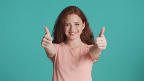 Redheaded-girl-looking-at-camera-on-turquoise-background.