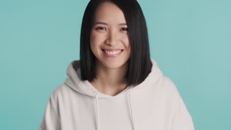 Asian-woman-in-sweater-smiling-on-camera.